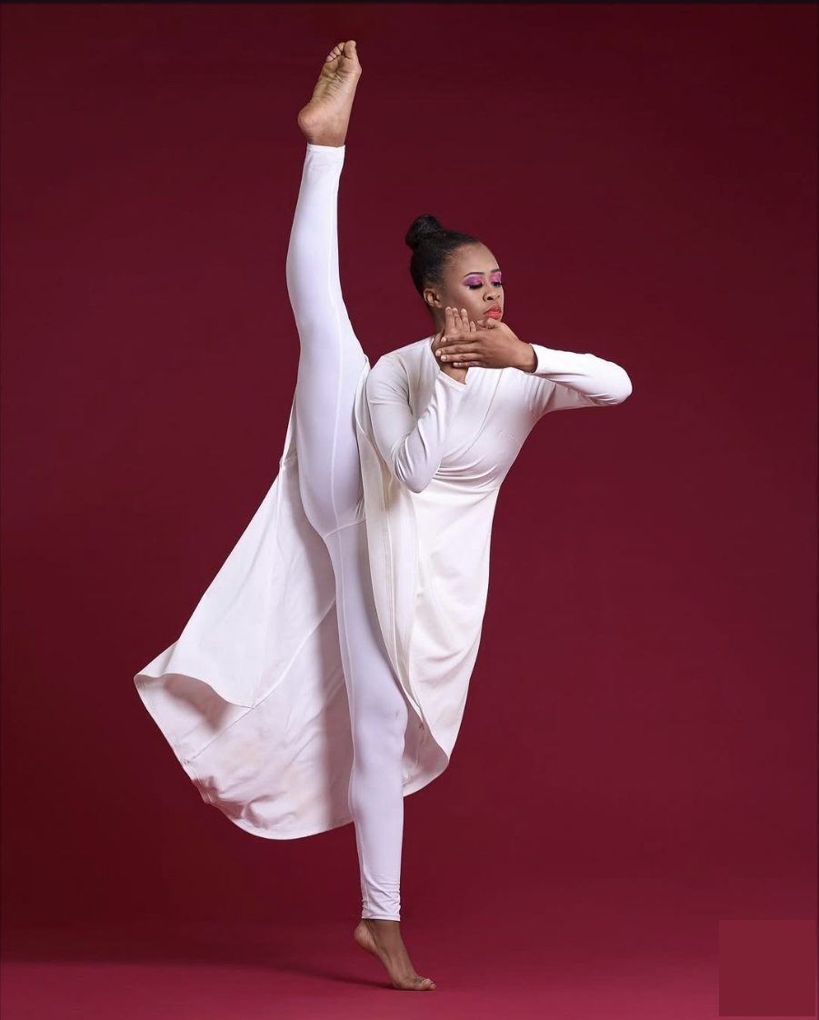 Amoni in white contemporary dance pose against crimson background